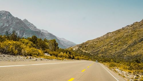 Road amidst trees and mountains against sky