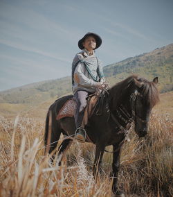 Portrait of man sitting on horse at land