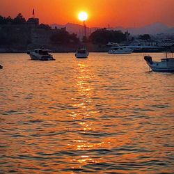 Boats moored on river against sky during sunset