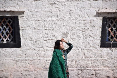 Side view of woman standing against wall