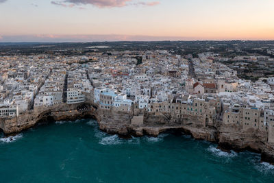 High angle view of townscape by sea against sky during sunset