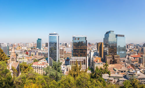 Buildings in city against clear blue sky