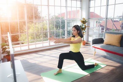 Young woman praticing yoga over television at home