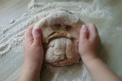 Close-up of dough with a faces and children hands