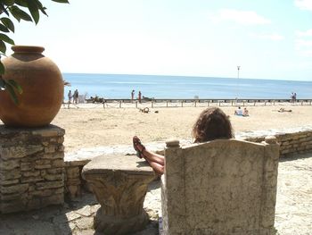 Rear view of woman on beach against clear sky