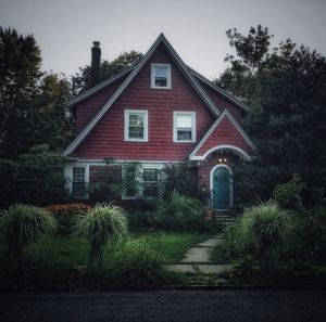 House amidst trees and building against sky