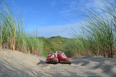 Shoes on sand against sky