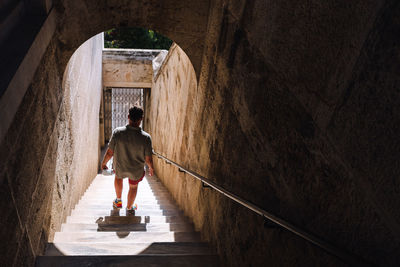 Rear view of woman walking in tunnel