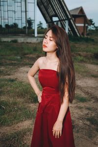 Young woman wearing red dress while standing on field