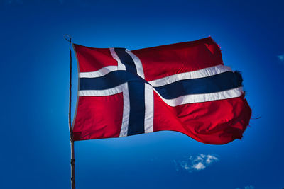 Low angle view of flag against blue sky