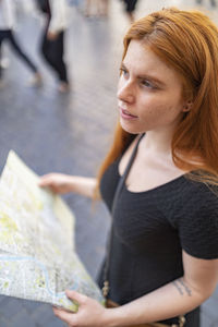 Portrait of a woman standing in the city holding a city map