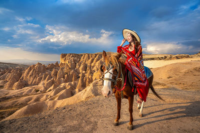 Beautiful woman wearing hat sitting on horse against sky