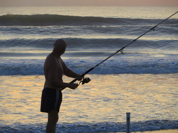 Man fishing in sea against sky