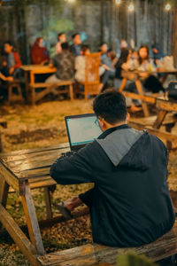 Rear view of man working on table