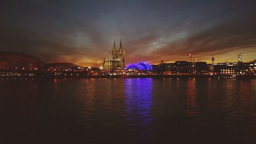 Cologne cathedral and illuminated cityscape by river at dusk