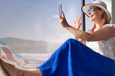 Woman using mobile phone while sitting at airport