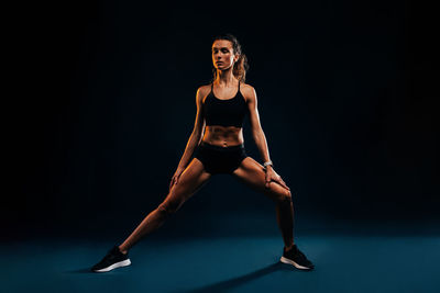 Determined athlete exercising against black background