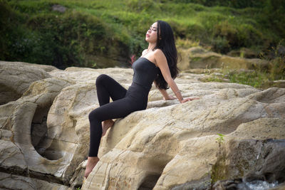 Full length of woman sitting on rock