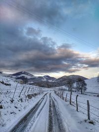 Snow covered road against sky during winter