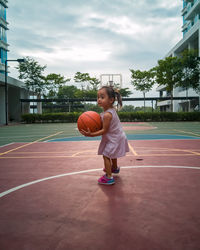 Full length of girl playing with basketball