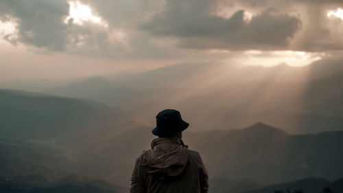 Rear view of man looking at landscape during sunset