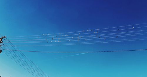 Low angle view of electricity pylon against blue sky