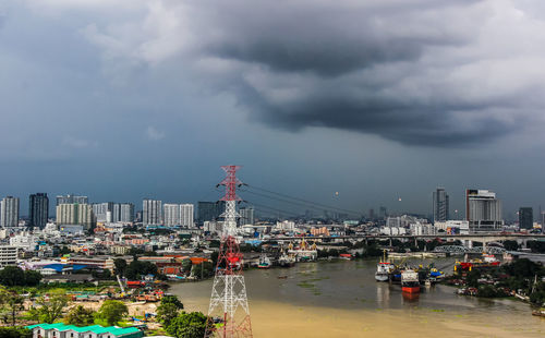 Boats moored at harbor against sky in city