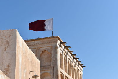 Low angle view of flag against clear blue sky