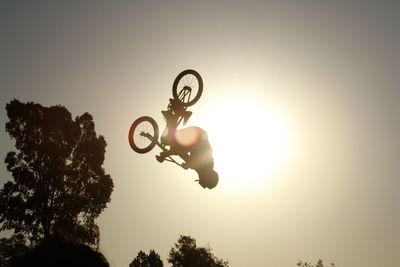 Low angle view of silhouette person paragliding against sky during sunset