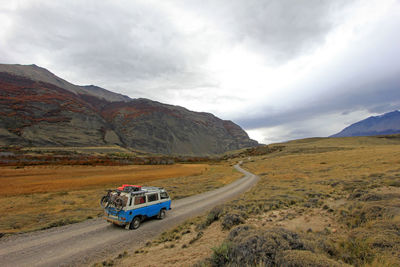 Car on road by mountain against sky