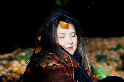 Close-up of young woman in autumn leaves