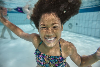 Portrait of smiling girl under water in swimming pool