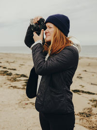 Woman taking photos on beach in scotland