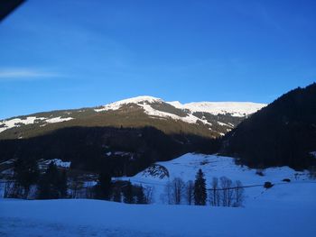 Scenic view of snowcapped mountains against blue sky