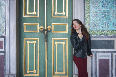 Young woman standing against closed door