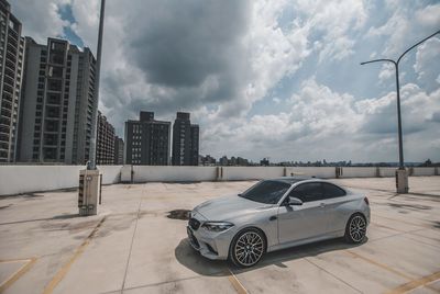 Car on street by buildings against sky