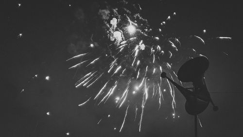 Low angle view of firework display over sea at night