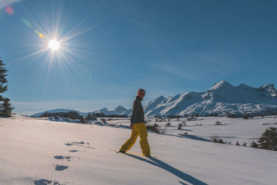 A full-body shot of a young caucasian woman walking towards the camera in the french alps mountains