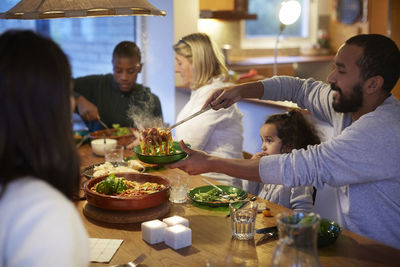 Father serving food while sitting with family at table