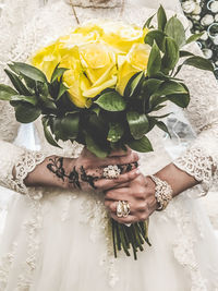 Midsection of bride holding bouquet