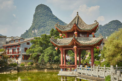 Traditional building by lake against sky