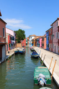 Boats moored on canal by colorful buildings at burano island