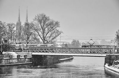 Railway bridge over river against sky during winter