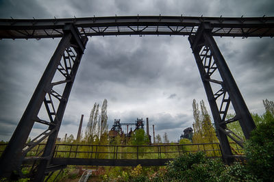 Low angle view of bridge against cloudy sky