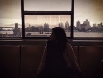 Woman looking at city through window