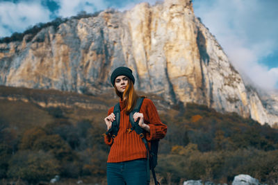 Young woman standing against mountain range