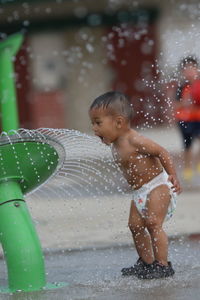 Full length of boy standing by water fountain