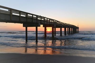 Pier over sea against clear sky during sunset