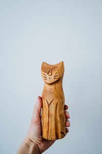 Midsection of person holding wooden sculpture against white background