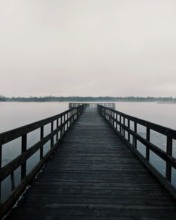 Wooden pier over sea against sky